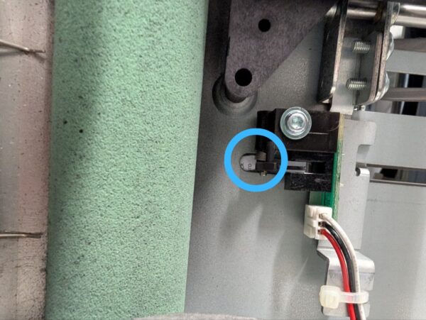 Ein kleiner, eingekreister Papierschnipsel im tiefen Inneren des Falzmoduls einer Quadient DS-40 Kuvertiermaschine.